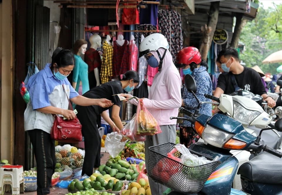 A vendor and customer exchanging goods at a Vietnamese open-air market